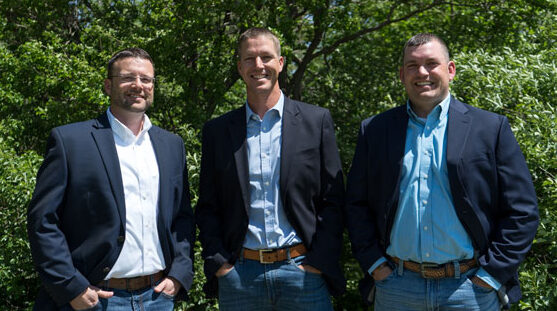 HPFC Loan Officers including Eric Fox, Ben Ramsey, and Ryan Rewerts, stand smiling in front of a background of green trees.