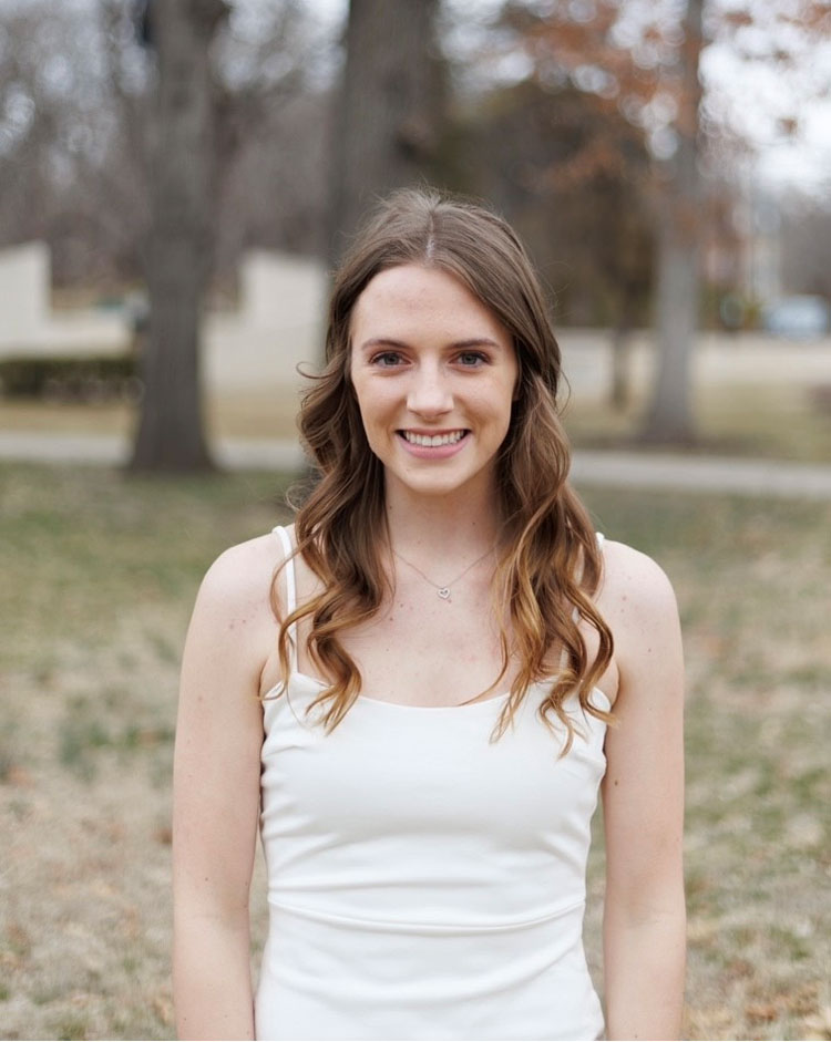 Regan Ast stands against a blurred background of fall grass and trees.
