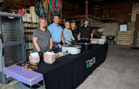 HPFC staff from the Larned office serve biscuits and gravy from behind a table bearing the High Plains Farm Credit logo.