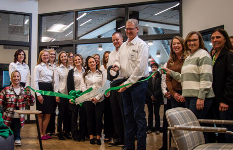 HPFC President and CEO, Kevin Swayne, cuts the ribbon on the new office in Hays. Staff and community members gather in the background.