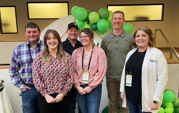 HPFC Vice President Loan Officer, Sarah Linenberger, poses with young, beginning, and small borrowers in front of a balloon-covered sign at the GYFF event.