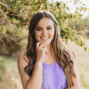 Outdoor photo of Kelsey Selensky posed in front of a tree.
