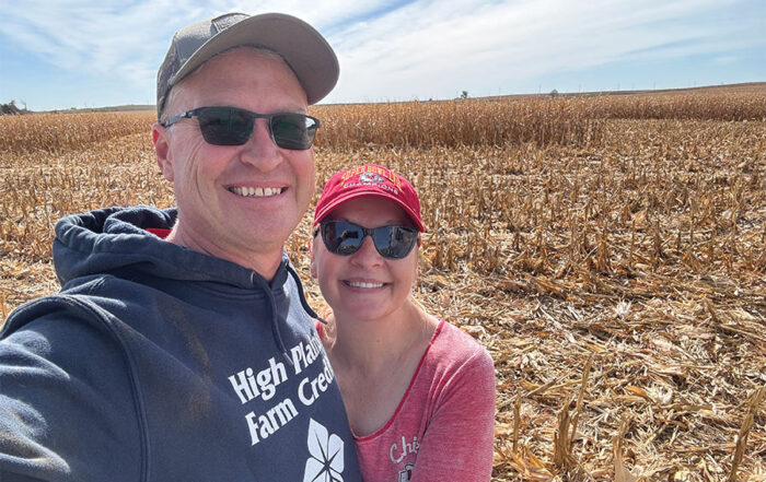 HPFC President and CEO, Kevin Swayne, stands smiling beside his wife, Jo. A corn field ready for harvest makes up the background.