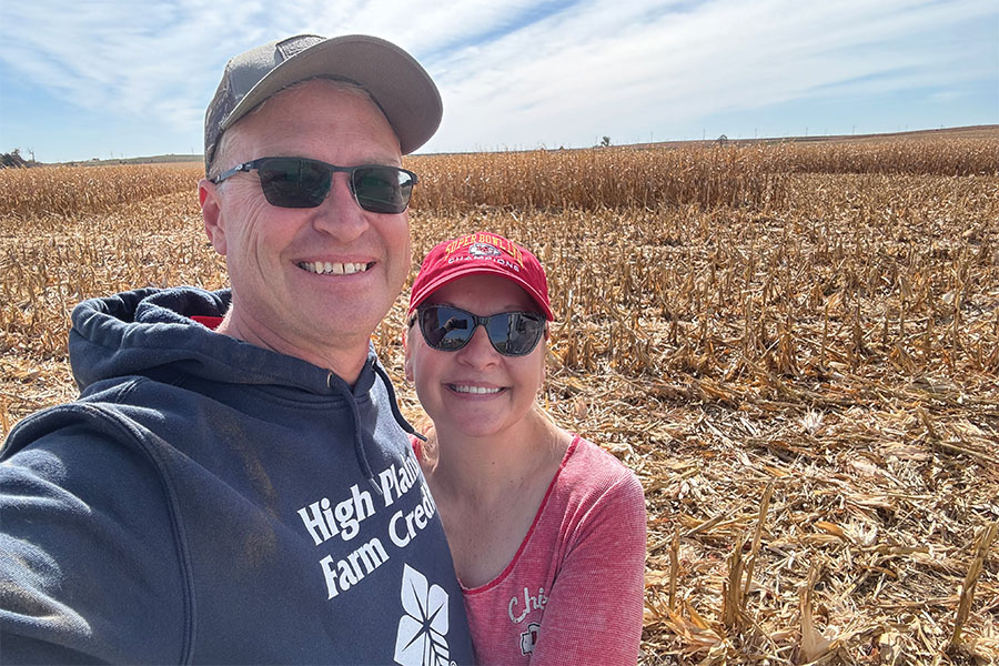 HPFC President and CEO, Kevin Swayne, stands smiling beside his wife, Jo. A corn field ready for harvest makes up the background.