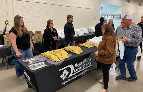 Members of the HPFC Hays office greet local farmers from behind a table topped with stacks of leather gloves.