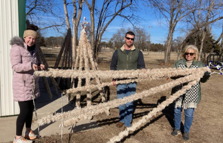 Members of the HPFC team in Pratt hold a tall Christmas tree lighting display on its side as they help with teardown after Christmas.