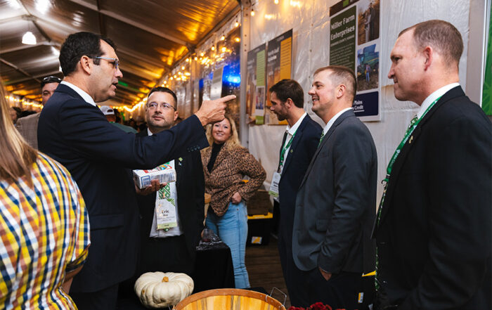 High Plains Farm Credit staff, directors, and customers talk with Kansas Representative Derek Schmidt during the 2025 Farm Credit Marketplace Reception. Representative Schmidt holds a bag of Hudson Cream Flour, the product that HPFC displayed during the event.