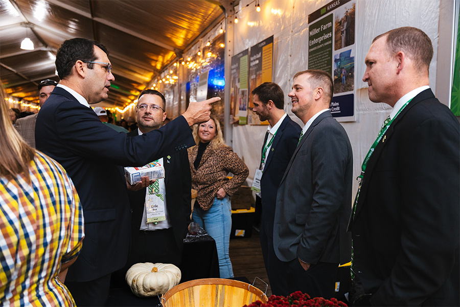 High Plains Farm Credit staff, directors, and customers talk with Kansas Representative Derek Schmidt during the 2025 Farm Credit Marketplace Reception. Representative Schmidt holds a bag of Hudson Cream Flour, the product that HPFC displayed during the event.