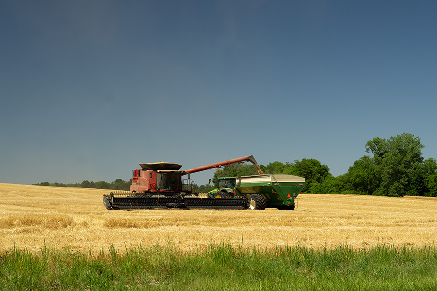 Combine unloads wheat into a grain cart during harvest time, an important season to have an operating line of credit for consistent cash flow.