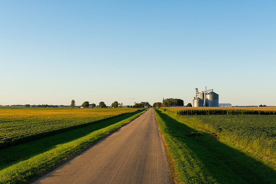 Scenic view of grain silos and a rural farm on a dirt road illustrating country home loans and rural lifestyle.