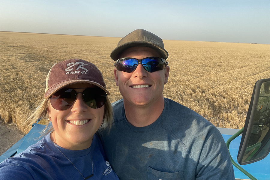 Lindy McMillen and her husband take a selfie in front of a wheat field that is ready to be harvested.